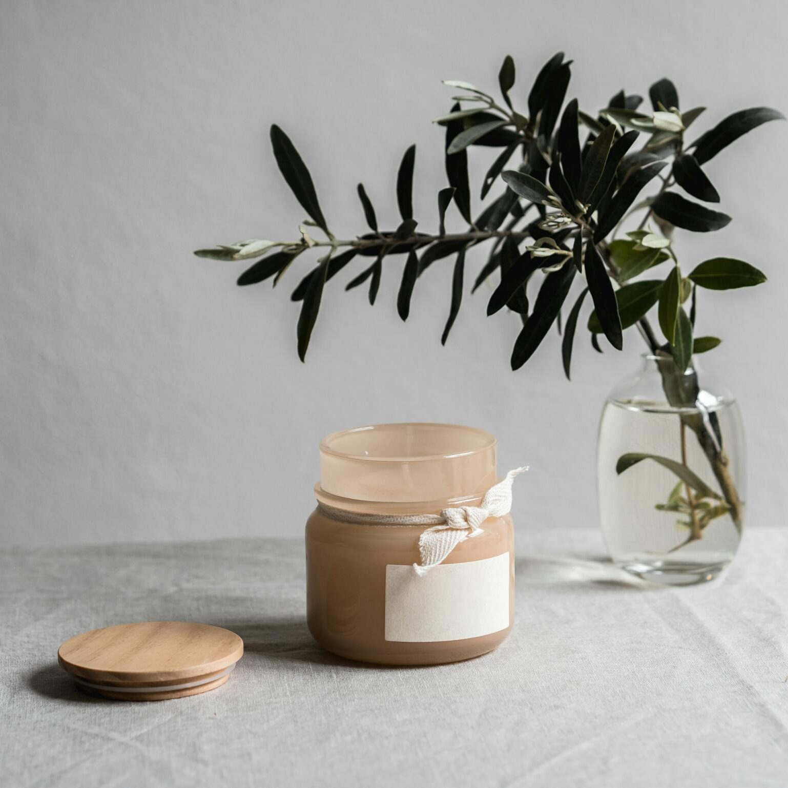 Minimalist photograph of a jar with foliage against a neutral background, ideal for product showcases.